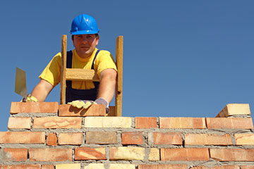 a brick mason building a brick wall