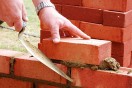 a bricklayer laying brick, building a brick wall